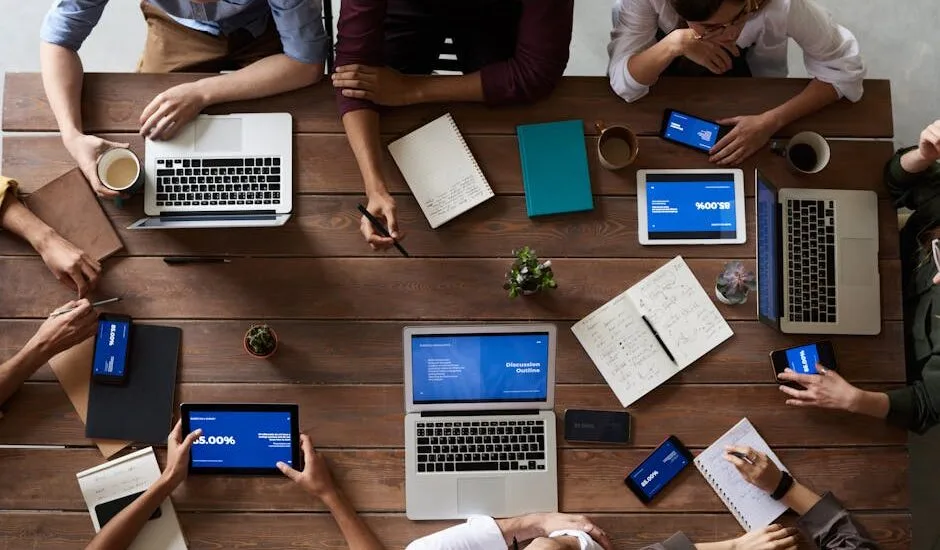 Overhead view of a diverse team in a business meeting using laptops and tablets.