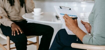 Two professionals engaged in a consultation, one taking notes on a clipboard.